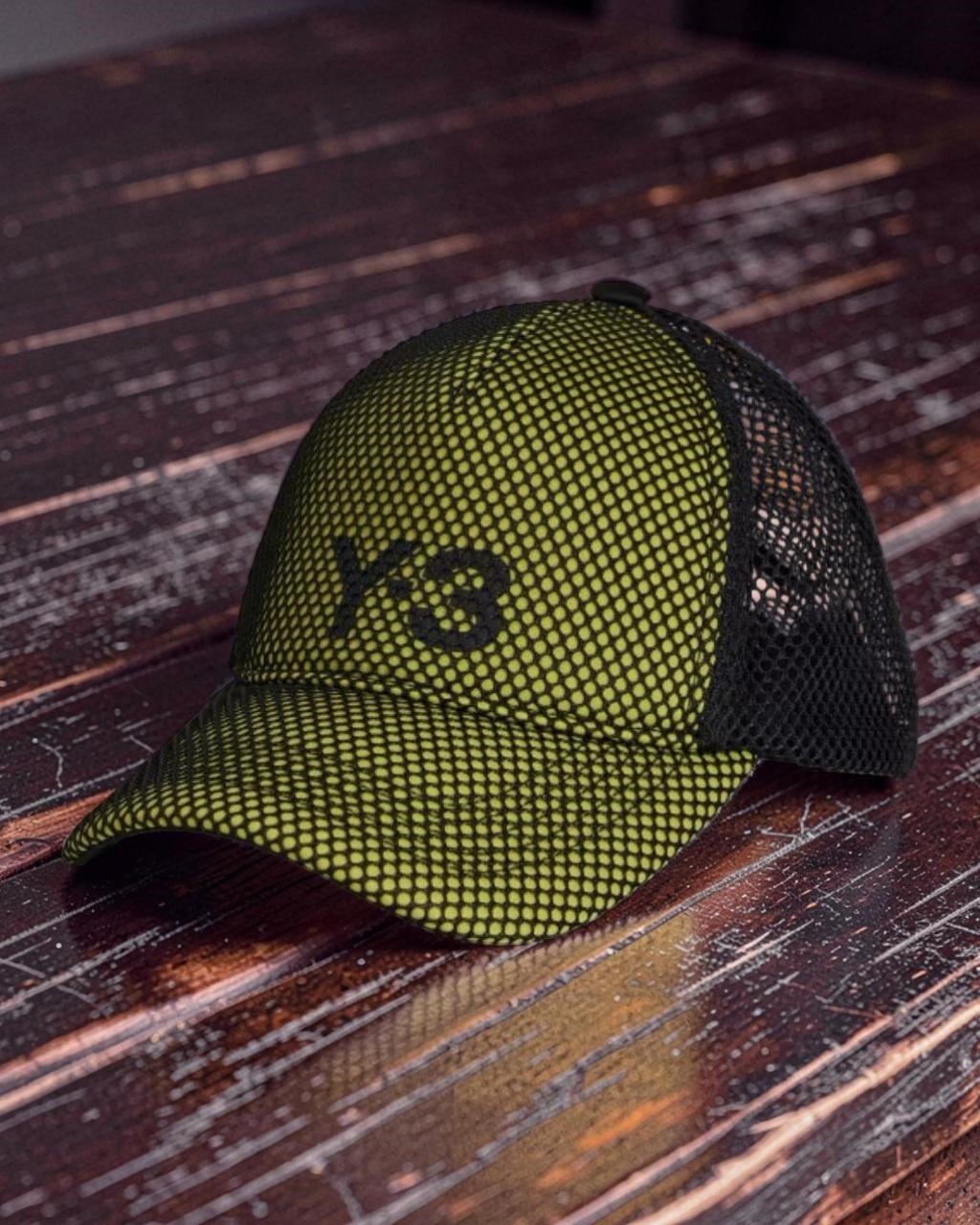 Y-3 Green Trucker Cap with black mesh angled front view resting on dark wood